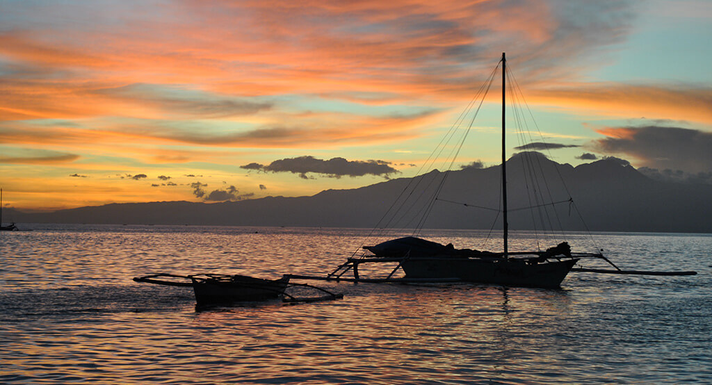 Coucher de soleil sur la mer avec un bateau à Siquijor.